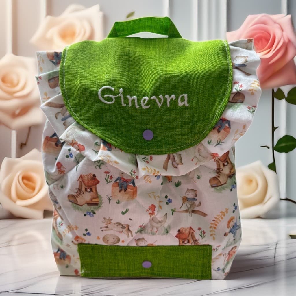 Zainetto bianco con motivi di animali, patta verde con nome Ginevra ricamato e rose decorative.